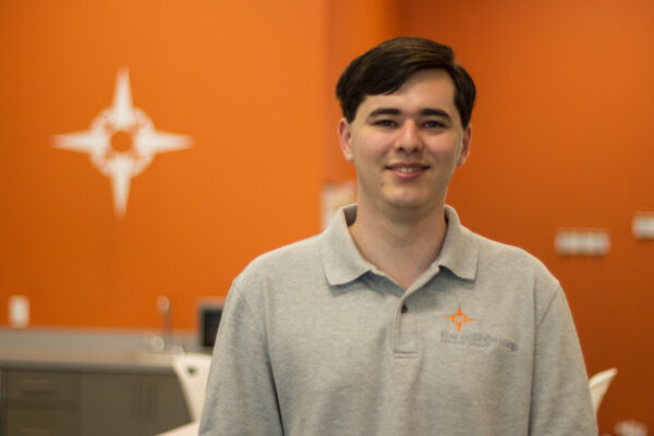 Smiling man in gray polo with orange background Smiling man in gray polo with orange background